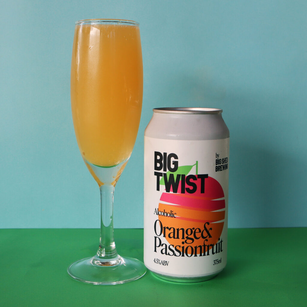 Can of Big Twist Orange and Passionfruit next to a mimosa in a champagne glass